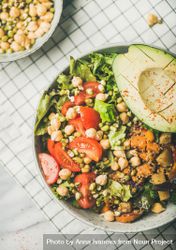 Healthy vegan lunch bowl with avocado, grains, vegetables, on checkered napkin bYvlg0