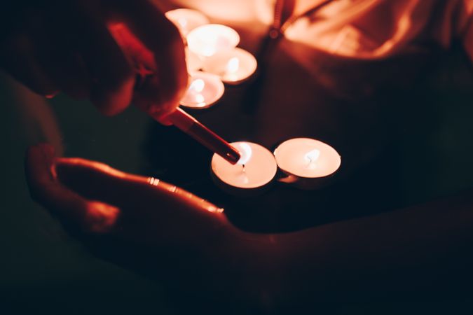 Crop person lighting candles in pool