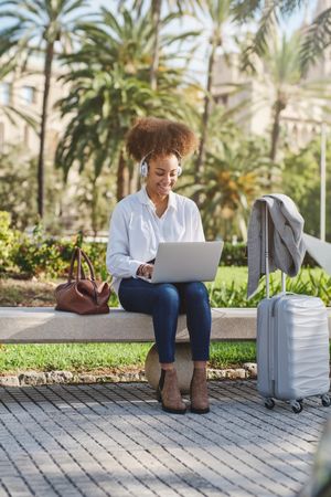 Young Black female freelancer working on laptop in park