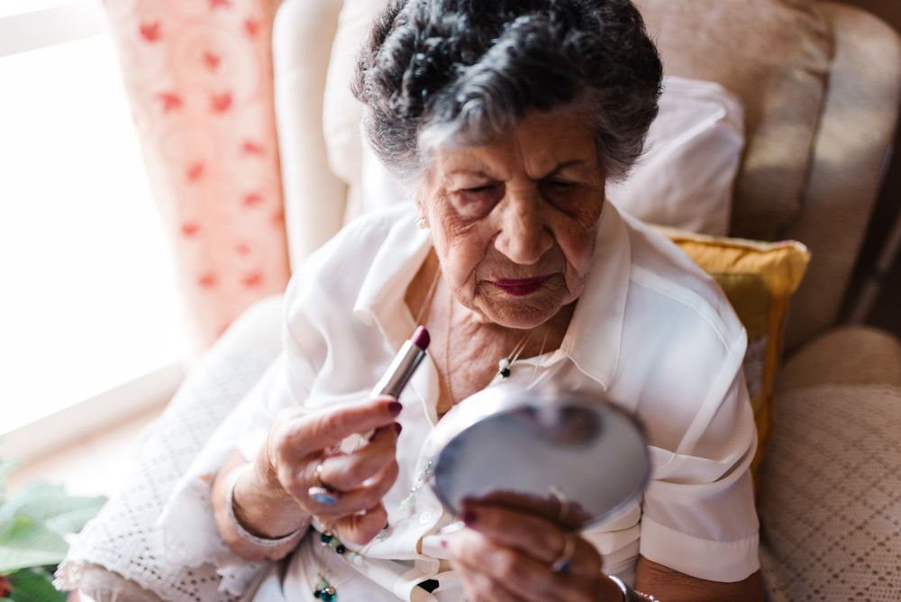 Older woman doing lips makeup at home