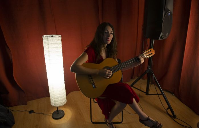 Creative woman singing and playing guitar on stage