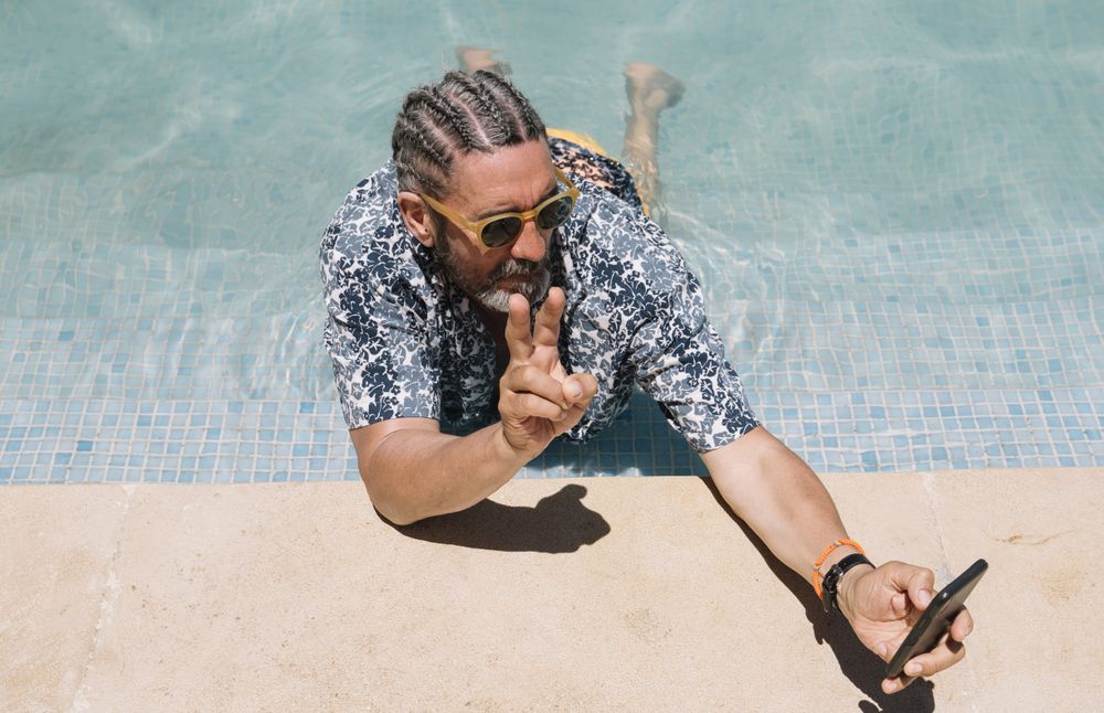 Older man using smartphone in swimming pool