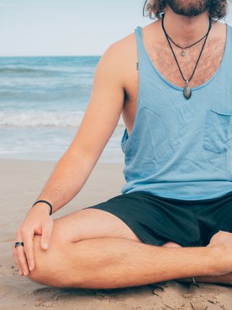 Man training yoga on beach