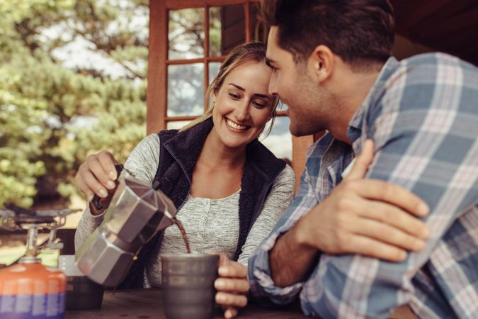 Happy young woman serving coffee to her boyfriend