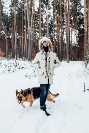 Man in winter coat on snowy day with dog