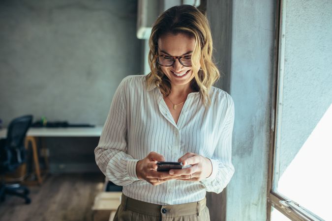 Female entrepreneur looking at her mobile phone and smiling