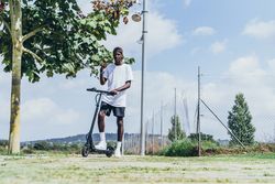 Black man riding on electric scooter in park