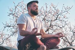 Bearded man meditating in spring garden
