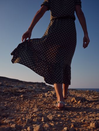 Crop woman walking on stony coast