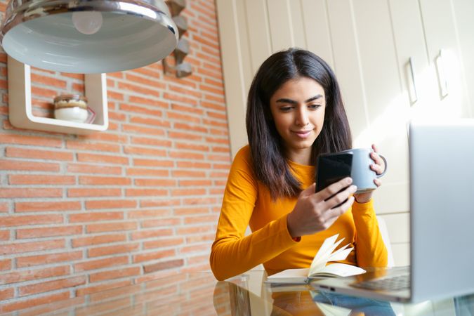 Woman sipping coffee while working in home office