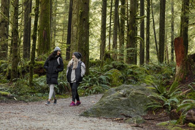 Happy young female and woman talking while hiking in a forest