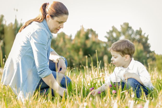 Pregnant mother and son picking flowers in a field