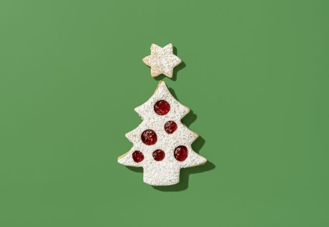 Christmas tree shaped cookie on a green background, top view
