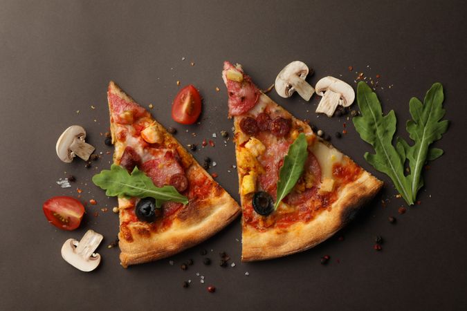 Pizza slices and ingredients on dark background