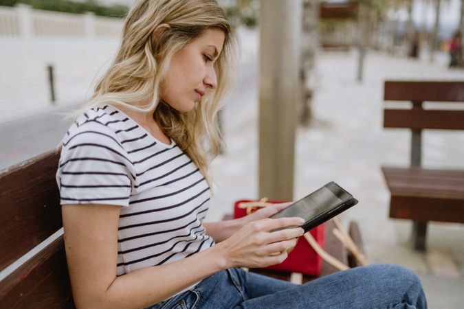 Woman sitting on bench and using tablet