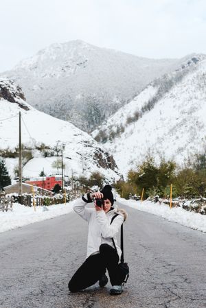 Content woman taking picture in snowy mountains