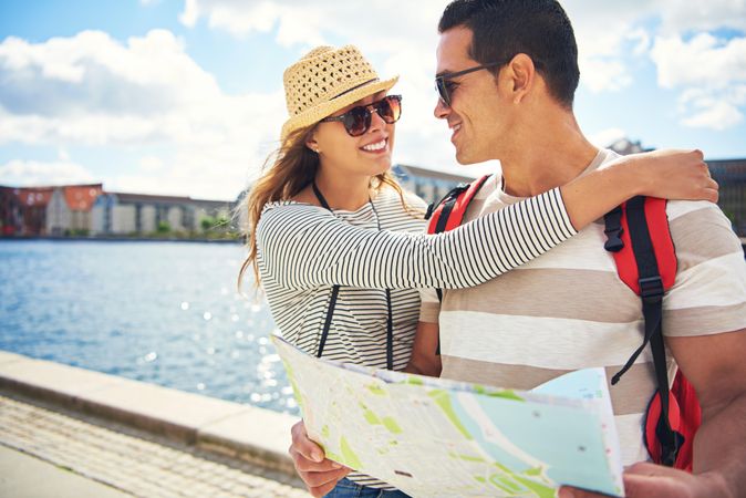 Smiling couple embracing while holding a map