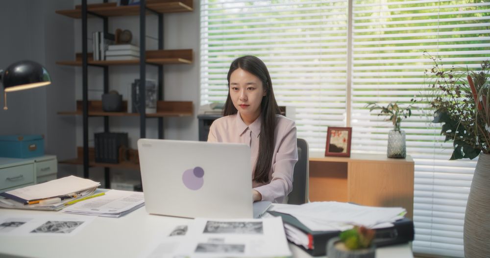 Portrait of a South Korean Female Working on a Computer Behind a Desk in a Stylish Creative Agency.