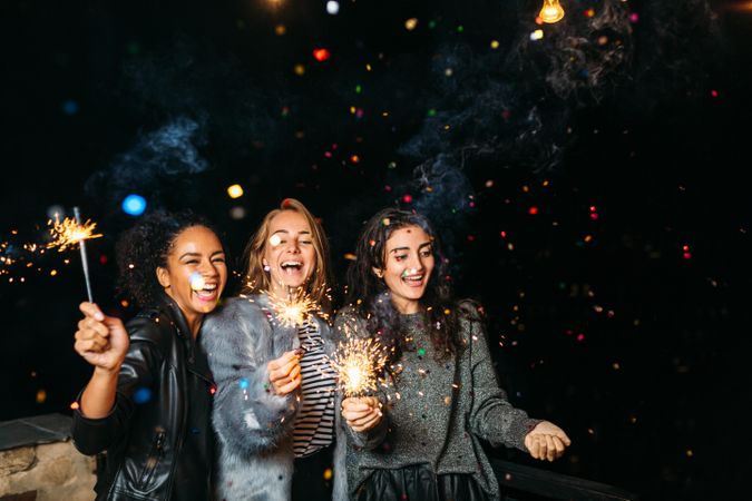 Multi-ethnic group of smiling women at a party with  sparklers