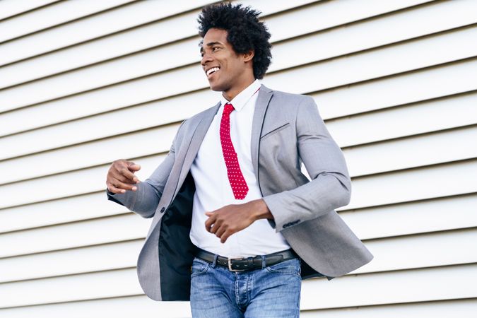 Happy man in jeans and dress shirt with tie smiling outside