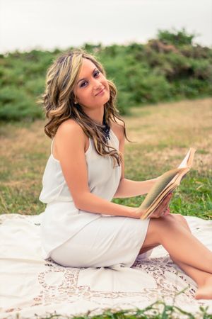 Romantic woman reading a book sitting outdoors