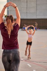 Sportive women training little girl on sport ground