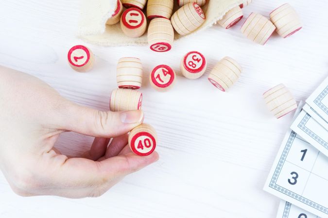 Person holding small wooden pieces with numbers on them