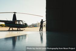 Man opening the door of the helicopter hangar 4BoqMb