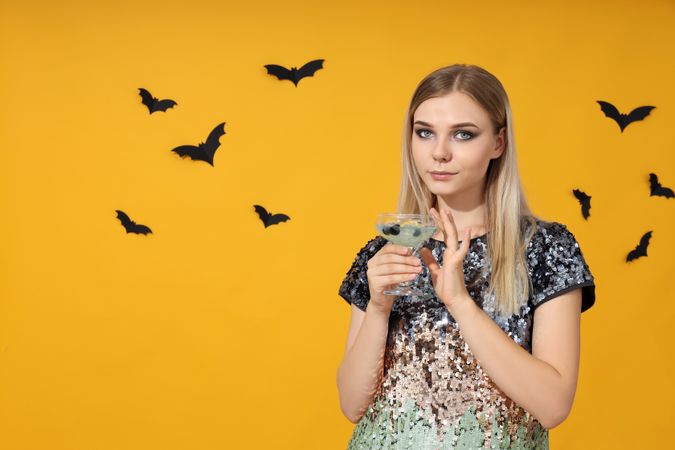 Concept of Halloween, young woman on yellow background