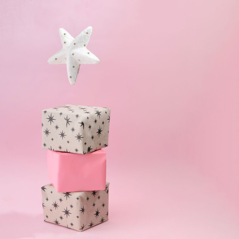 Christmas presents piled on soft pink background