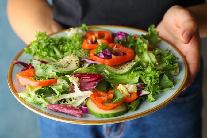 Young woman in jeans holding salad, close up