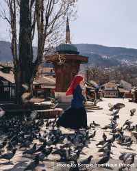 Woman wearing hijab standing among pigeons outdoor bGBzx4