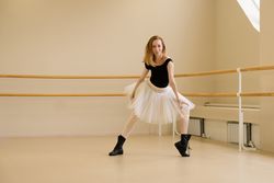 Ballerina in shoes and tutu, crouching in modern dance style.