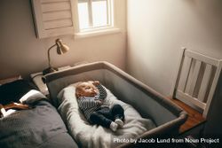 Baby sleeping in a bedside bassinet in bedroom bDaVK0