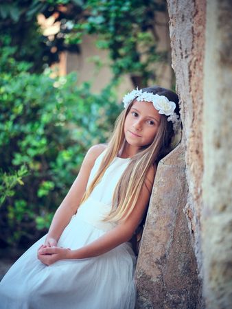 Charming woman in bridal dress leaning on building wall