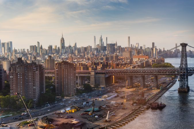 New York City Landscape Over East River with Upper East Side Skyscrapers and Ed Koch Queensboro Bridge. Cinematic Urban Skyline with Sunny Lightly Clouded Sky