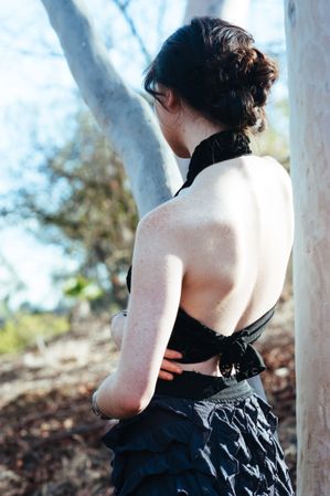Back view of woman’s shoulders and back in open-backed shirt in the woods