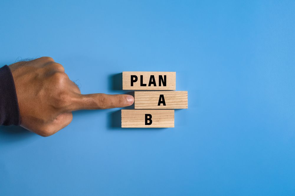 male hand pointing plan a or b on wooden blocks isolated on blue background. concept of business strategy planning