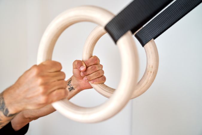 Crop sportsman with gymnastic rings in gym