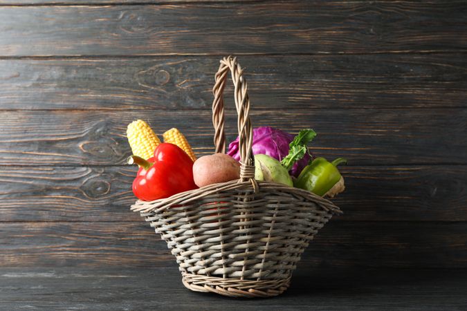 Wicker basket with vegetables on wooden background, copy space