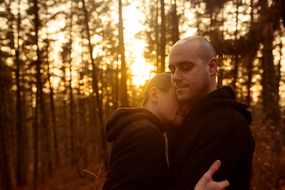 Men hugging in forest at sunset