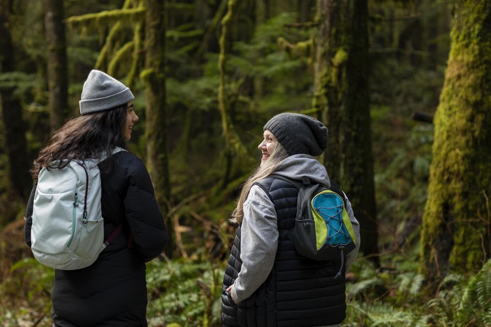 Young female and woman talking and hiking in mossy forest