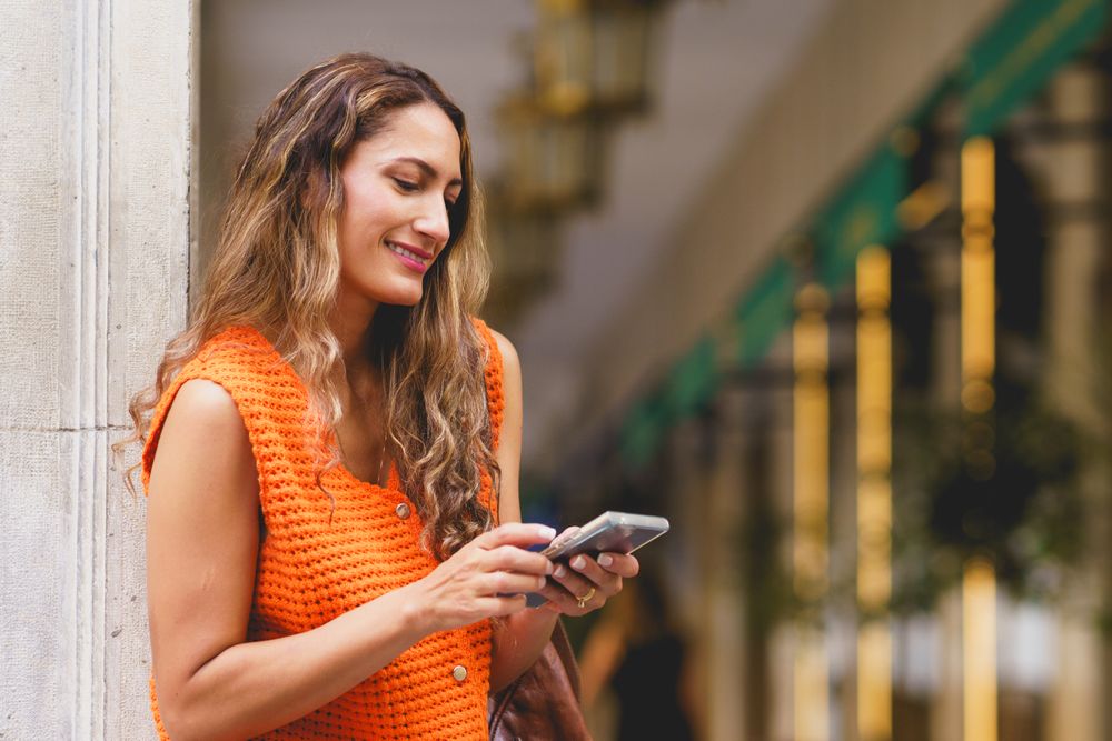 Woman using phone smiling in the street