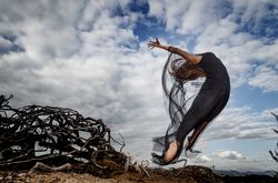 Woman posing in air near dry twigs and blue sky