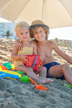 Smiling boy hugging little girl on beach in summer