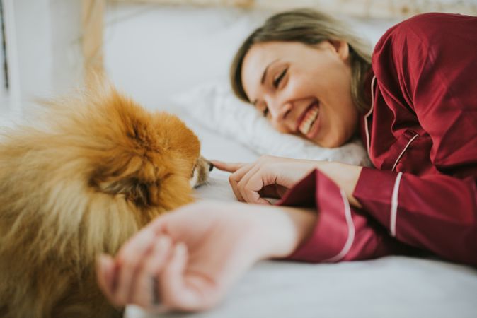 Smiling woman lying in bed with dog