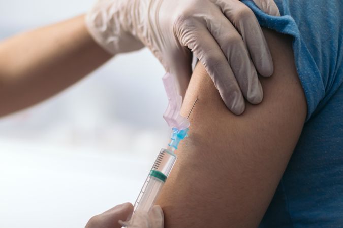 Vaccine in injection needle. Doctor working with patient's arm.