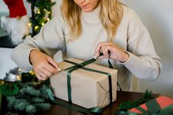 woman wrapping christmas gift at home