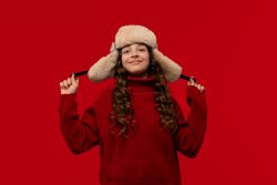Happy girl in fur hat confidently holds ear flaps hat