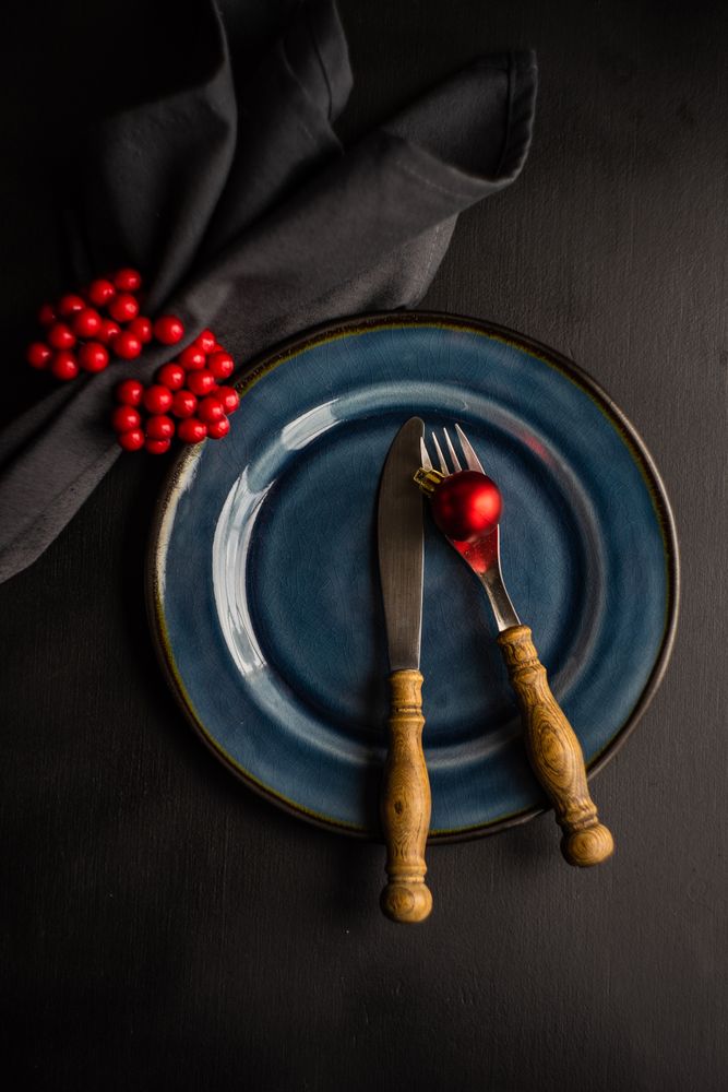 Navy plate on dark table with red decorative baubles and berries